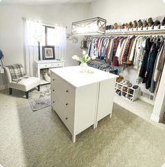 a white closet with clothes hanging on the wall and two chairs in front of it