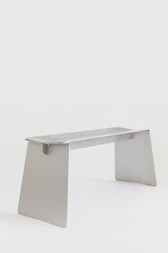 a silver bench sitting on top of a white floor next to a wall and window