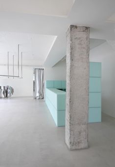 an empty room with concrete columns and blue cabinets in the center, along with white walls