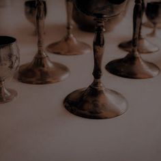 a row of silver goblets sitting on top of a white table next to each other