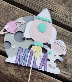 a cake topper with the word mia on it and an image of a rocket ship