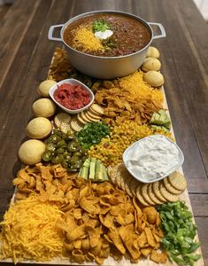 a platter filled with chips, salsa and dips on top of a wooden table