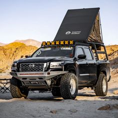 a black truck parked in the desert with its hood open and lights on it's roof