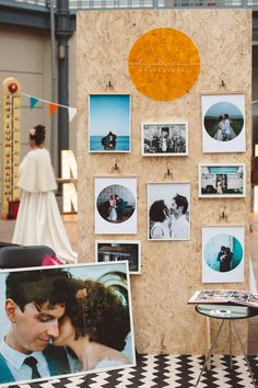 a couple kissing in front of a wall with pictures on it