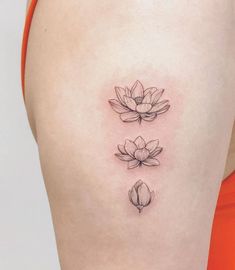 a woman's thigh with three lotus tattoos on it