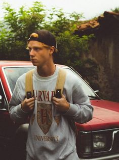 a young man walking past a red car