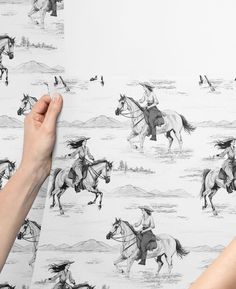 two hands are holding up a wallpaper with horses on it