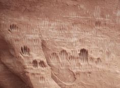 two people are standing in front of a rock formation with their hands and feet carved into it