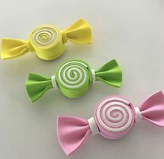 three candy lollipops in different colors on a white table with yellow, pink and green candies