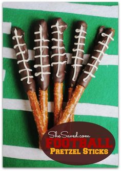 four pretzel sticks decorated like footballs on a green and white striped towel