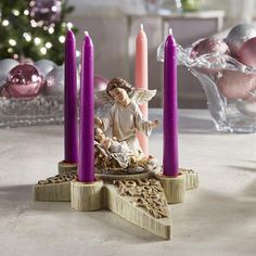 an angel figurine sitting next to purple candles