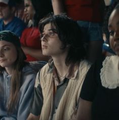 three people sitting next to each other in front of an audience at a sporting event