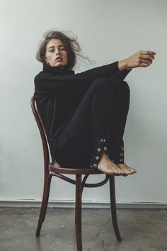 a woman sitting on top of a wooden chair