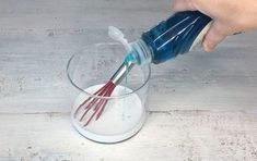 someone is using a blue and red brush to mix something in a glass with white liquid