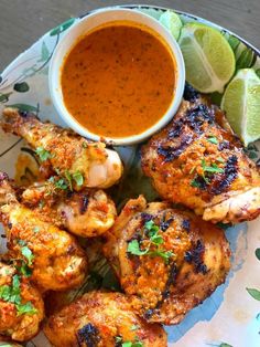 grilled chicken wings with dipping sauce and garnishes on a blue plate