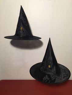 two black witches hats are hanging on the wall next to a red table with a clock