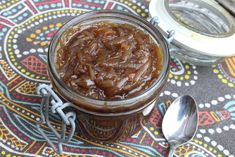 a glass jar filled with food sitting on top of a table next to two spoons