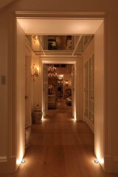 the hallway is lit up with lights and wood flooring, along with white walls