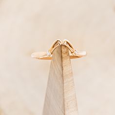 a gold ring sitting on top of a piece of wood with two diamonds in it