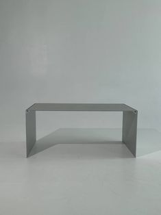 a white table sitting on top of a floor next to a gray wall in an empty room