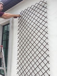 a man is painting the side of a building with metal bars on it's sides