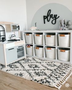 a play room with toy kitchen and storage bins on the floor next to it