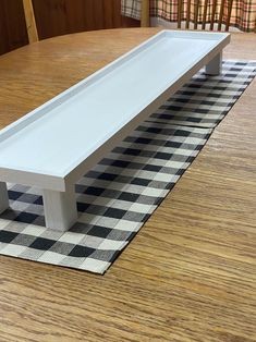 a white bench sitting on top of a checkered tablecloth in front of a window