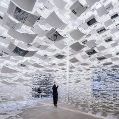 a person standing in a room with lots of papers hanging from it's ceiling