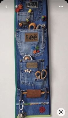 an old pair of jeans hanging on a wall with some scissors and other items in it