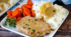 a white plate topped with mashed potatoes, carrots and gravy on top of a wooden table