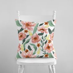 a white chair with a pink flowered pillow sitting on it's backrest