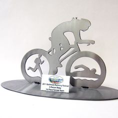 a metal sculpture of a man riding a bike with a dog on it's back