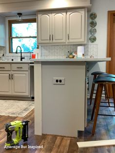 a kitchen with white cabinets and wood floors