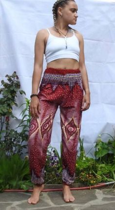 a woman standing in front of a white wall wearing red and purple pants with an intricate design on the bottom