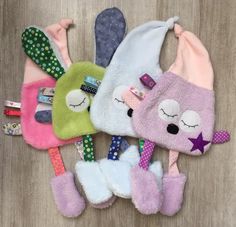 four small stuffed animals laying on top of each other in different colors and sizes,