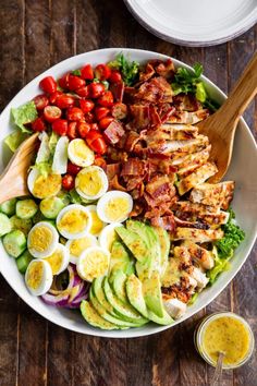 a salad with hard boiled eggs, bacon, avocado and tomatoes in it