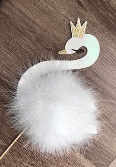 a white swan with a crown on it's head sitting on top of a wooden table