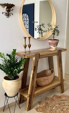 a wooden table with a mirror and potted plants on it in front of a door