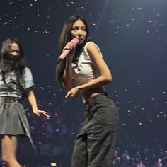 two women on stage with microphones and confetti in the background