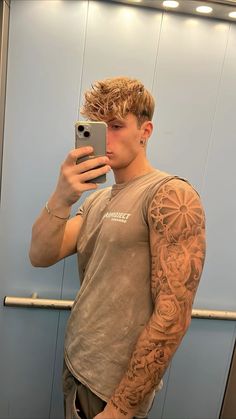 a man taking a selfie in front of a mirror with tattoos on his arms