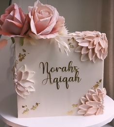 there is a cake decorated with flowers on top of a table and the words, nohar aagaah written in gold