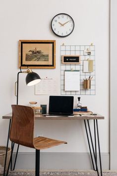 a desk with a laptop computer sitting on top of it next to a wall mounted clock