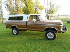 a brown and white truck parked on top of a lush green field