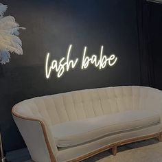 a white couch sitting in front of a neon sign that says cash baube