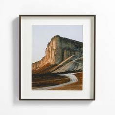 a framed photograph hanging on the wall next to a white wall with a dirt road in front of it