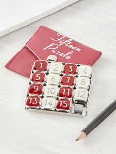 a red and white calendar sitting on top of a table next to a pencil