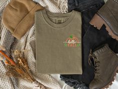 Left chest embroidered Pumpkin outline with Hello Fall.   This is a premium tee from Comfort Colors. Photo shows the shirt color in Khaki, Pepper and Yam.  Stitched in vibrant autumn colors, browns, pumpkin, moss green and ivory, it screams Fall and Autumn!    - Comfort Colors Unisex sizing - Embroidered design Please message me with any questions! Casual Embroidered Fall T-shirt, Casual Embroidered T-shirt For Fall, Casual Fall T-shirt With Embroidered Logo, Casual Embroidered Logo T-shirt For Fall, Casual Tops With Embroidered Logo For Fall, Fall Cotton T-shirt With Embroidered Graphics, Fall Embroidered Graphics Cotton T-shirt, Fall Embroidered Graphic Tee, Embroidered Graphic Tee For Fall