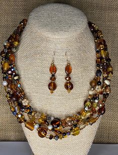 This beautiful shades of brown glass and gemstone necklace and earrings set for women features genuine several different kinds of beads in shades of  Brown, Gold, Black and Pearla.  This statement necklace has 5 loosely braided strands and is 20" long with a brass toggleclasp. It is a just gorgeous and is so perfect in its fall colors. There are matching earrings made with 14 K gold filled ear wires included with the purchase. It is one of my most popular pieces. This is a brown shaded glass and  gemstone statement necklace set with artisan dangle earrings on 14 k gold fill wires.  It is a bold, colorful,  boho beaded statement necklace for women   The trendy unique handmade earrings are nickel free and hypoallergenic.  Item Features: - Handmade necklace - 20 " long  - 5 strands - Glass, g Unique Handmade Earrings, Beaded Statement Necklace, Handmade Jewelry Gift, Colorful Boho, Necklace And Earrings, Handmade Necklace, Gold Pearl, Earrings Set, Brown Gold