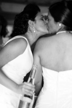 two women in white dresses kissing each other