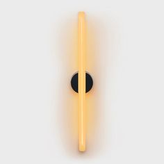 a black and yellow light is on the wall next to a round object that looks like a stick